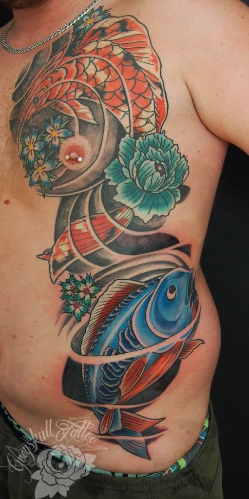 Rote und blaue Koi mit Blüten als großflächiges farbiges Tattoo am seitlichen Oberkörper